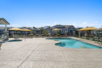 A swimming pool with patio furniture and umbrellas next to a resort style pool